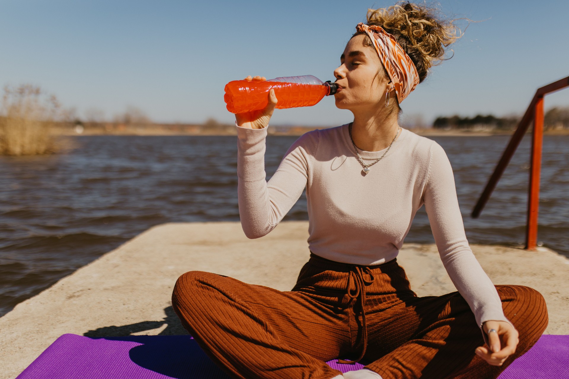 Young woman drinking juice while resting from workout